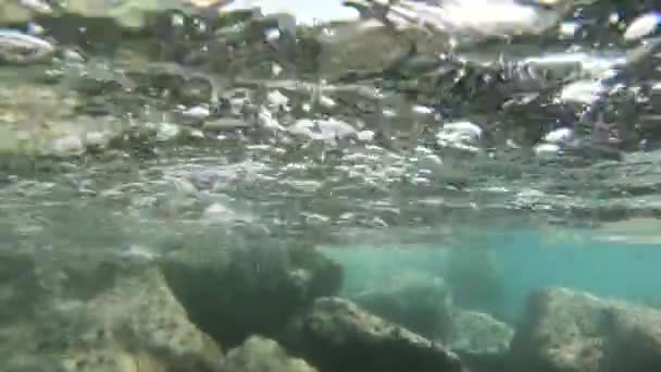 Disparo en cámara lenta bajo el agua con olas en la superficie del mar y piedras bajo el agua — Vídeos de Stock