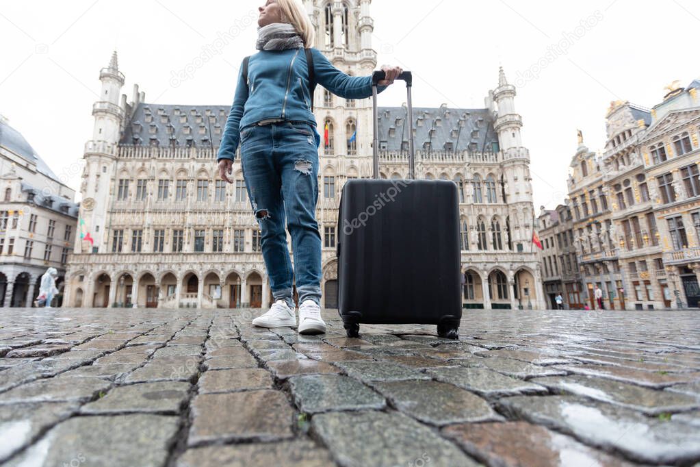 Woman tourist goes with a suitcase at the Grand Place in Brussels, Belgium