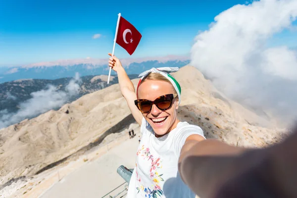 Joven turista se para en una plataforma de observación de la montaña Tahtali en Kemer con una bandera roja de Turquía, Turquía — Foto de Stock