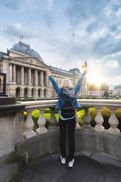 Mujer con las armas levantadas con la bandera de Bélgica se levanta sobre el telón de fondo del Palacio Real en Bruselas, Bélgica — Foto de Stock