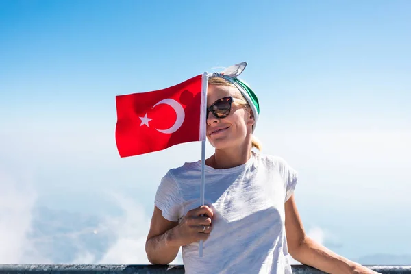 Young woman tourist stands on a viewing platform of Tahtali Mountain in Kemer with a red Turkey flag, Turkey — Stock Photo, Image