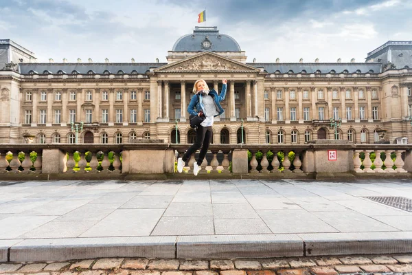 Woman jumps up on the background of the Royal Palace in Brussels, Belgium