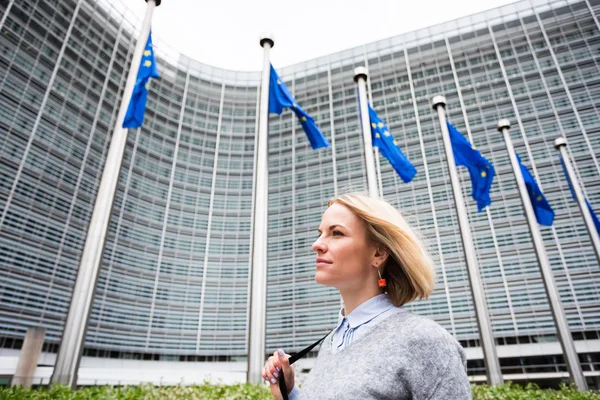 Een jonge vrouw staat tegen de achtergrond van het hoofdkwartier van de Europese Commissie in Brussel, België — Stockfoto