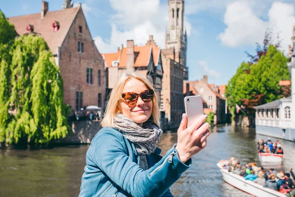 在比利时布鲁日的一个著名旅游胜地，一个漂亮的小女孩在一条运河的背景下自拍 — 图库照片