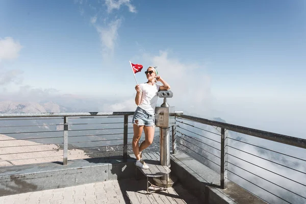 La giovane turista si trova su una piattaforma panoramica del monte Tahtali a Kemer con una bandiera rossa della Turchia, Turchia — Foto Stock