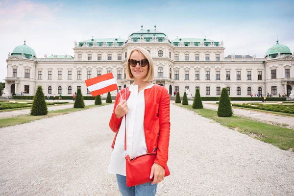 Uma jovem turista com a bandeira austríaca desfruta de um passeio por Viena no jardim do Complexo Belvedere Palace — Fotografia de Stock