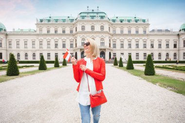 Avusturya bayrağı taşıyan genç bir bayan turist, Belvedere Sarayı Kompleksi 'nin bahçesinde Viyana turunun keyfini çıkarıyor.