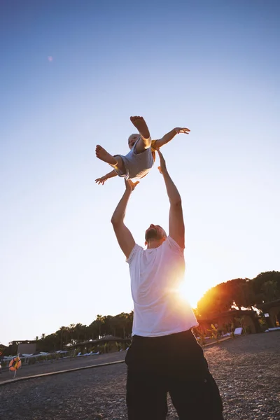 Pai e filho se divertindo na praia ao pôr do sol — Fotografia de Stock