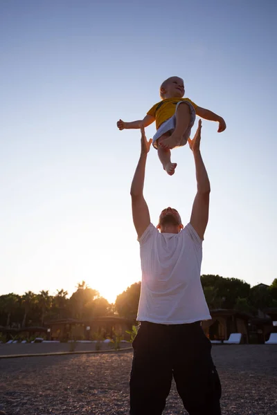 Pai e filho se divertindo na praia ao pôr do sol — Fotografia de Stock