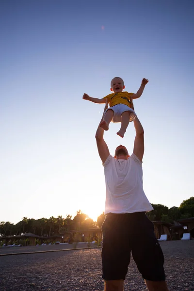 Pai e filho se divertindo na praia ao pôr do sol — Fotografia de Stock