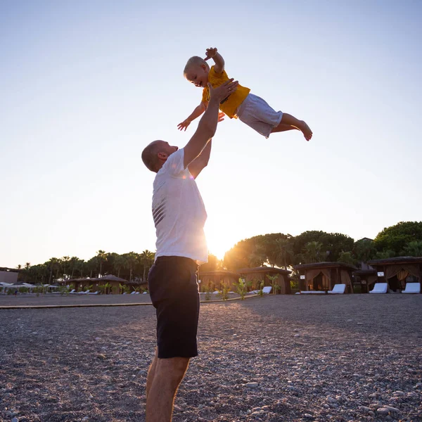 Pai e filho se divertindo na praia ao pôr do sol — Fotografia de Stock