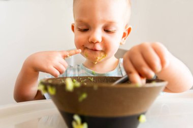 Küçük çocuk tabaktan püre yiyor..