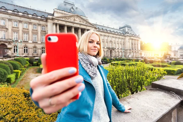Μια νεαρή γυναίκα στέκεται μπροστά από το βασιλικό παλάτι στις Βρυξέλλες και βγάζει μια selfie στο τηλέφωνό της, Βέλγιο — Φωτογραφία Αρχείου