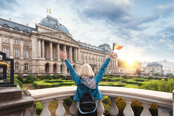 Mujer turista de pie con su espalda a la cámara y ondeando la bandera de Bélgica contra el fondo del Palacio Real en Bruselas — Foto de Stock