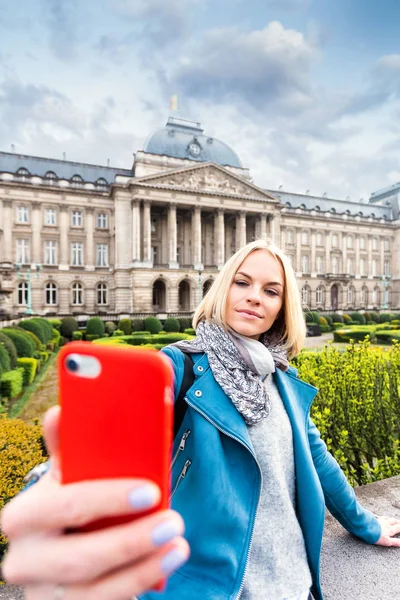 Μια νεαρή γυναίκα στέκεται μπροστά από το βασιλικό παλάτι στις Βρυξέλλες και βγάζει μια selfie στο τηλέφωνό της, Βέλγιο — Φωτογραφία Αρχείου