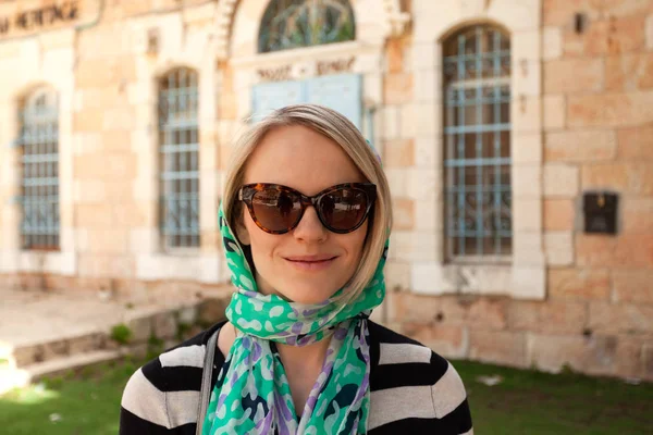 Uma jovem mulher crente está em um lenço perto da entrada de uma igreja em Jerusalém, Israel — Fotografia de Stock