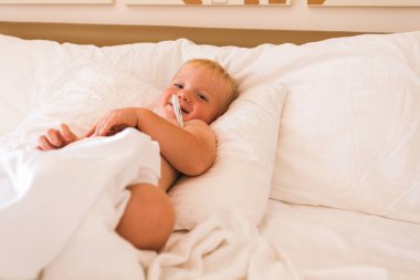 Çocuk yatakta yatar ve sıcaklığı ölçer.