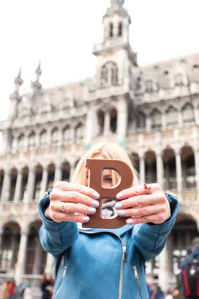 Mulher com barra de chocolate com leite em pé no Grand Place, em Bruxelas, na Bélgica . — Fotografia de Stock