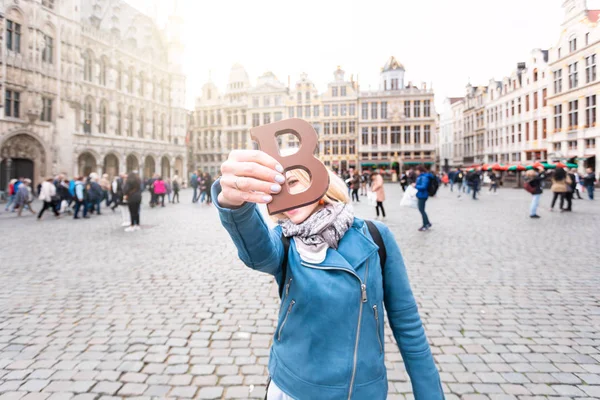 Mujer con barra de chocolate con leche de pie en el Grand Place en Bruselas en Bélgica . — Foto de Stock