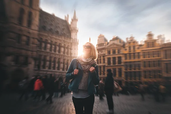 Woman stands in the square Grand Place in Brussels, Belgium at sunset.