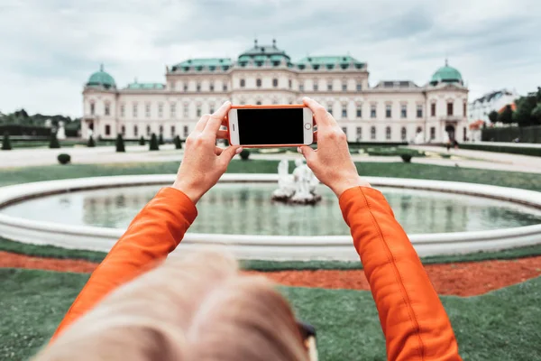 A young happy female tourist takes a photo against the backdrop of the Belvedere Palace in Vienna, Austria — 스톡 사진