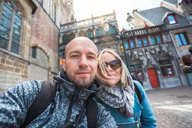 Belçika, Bruges 'deki Burg Meydanı' ndaki Kutsal Kan Bazilikası 'nın arka planında genç bir çift turist var..