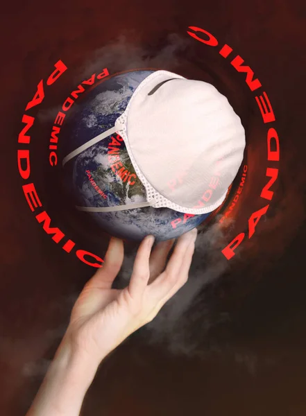 A hand holds the globe with a medical mask during an epidemic of Covid 19 or coronavirus worldwide. Concept