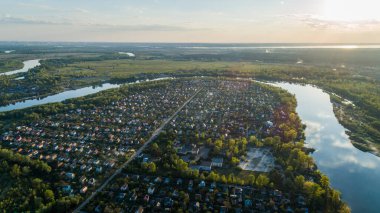 Yeşil çayır ve gün batımında bir nehir ile doğanın panoramik hava manzarası.