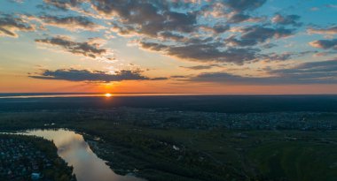 Yeşil çayır ve gün batımında bir nehir ile doğanın panoramik hava manzarası.