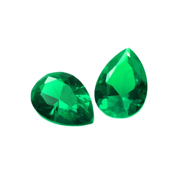 Two pear shaped emeralds on a wgite background.