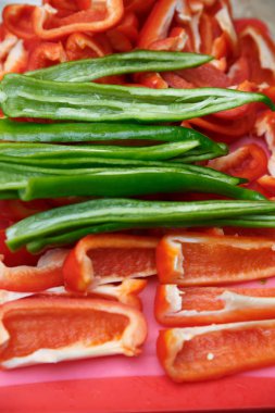 Doğranmış kırmızı biber ve acı yeşil biber kesme tahtasının üzerinde yatıyor.