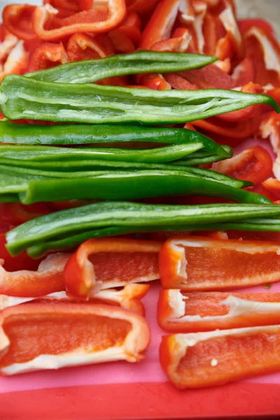 Doğranmış kırmızı biber ve acı yeşil biber kesme tahtasının üzerinde yatıyor.