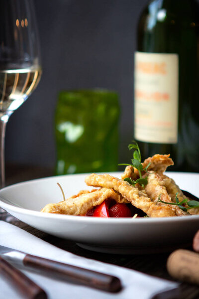 white fish fried in slices with vegetables on a white plate