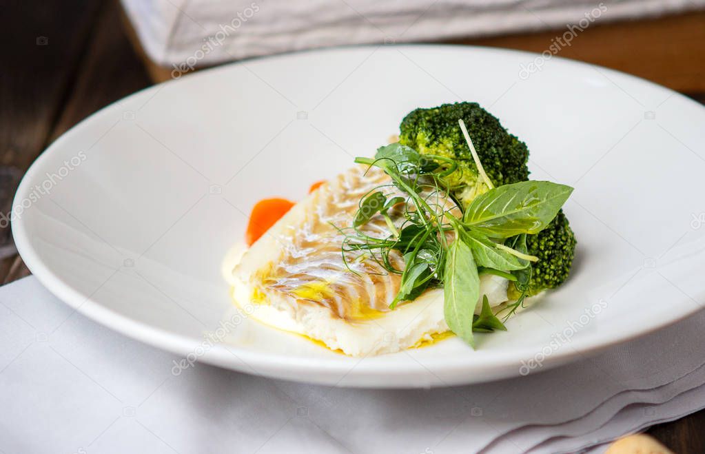 Cod fish fillet with mashed potatoes and broccoli on a white pla