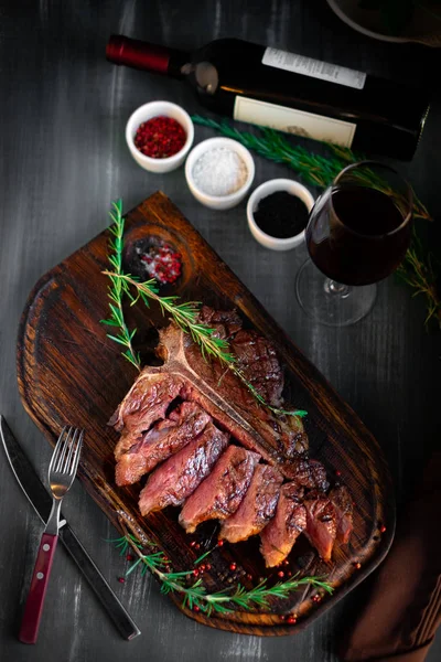 Bife grelhado em T-bone em tábua de madeira com vinho tinto — Fotografia de Stock