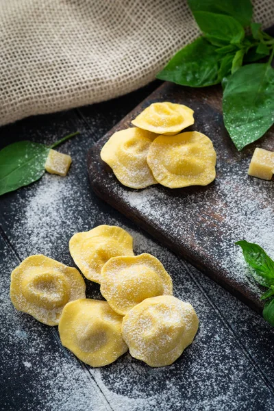 Ravioli crudi con formaggio e basilico cosparsi di farina su legno — Foto Stock