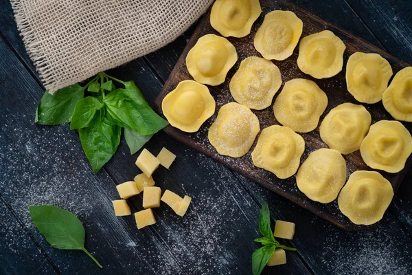 Verse ravioli met kaas en basilicum op een houten plank — Stockfoto
