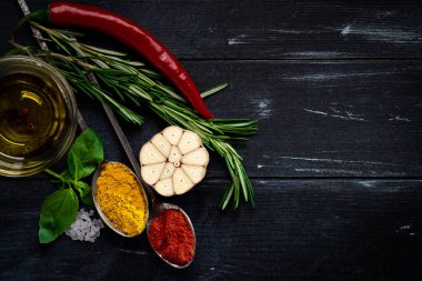 Metal kaşıkta çeşitli baharatlar. Köri, zerdeçal, biberiye, sarımsak, kırmızı biber, biber, tuz, fesleğen, ahşap kaplama kekik. Bitkisel, üst görünüm ve kopyalama alanı koleksiyonu