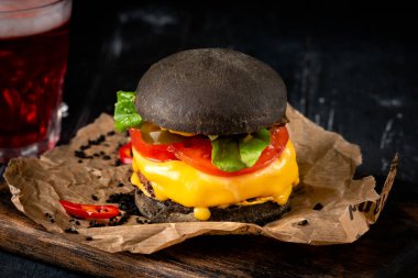 Tahta tahtanın üzerinde siyah ekmekli çizburger, ev yapımı Japon Burger.