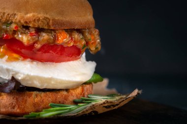 Ahşap bir tahta üzerinde kızarmış patlıcan, domates, marul, avokado ve mozzarella peynirinden yapılmış vejetaryen burger. Kapat ve boşluğu kopyala