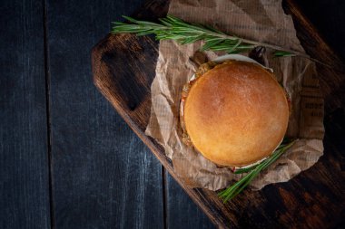 Koyu arka planda, ahşap bir tahtada ev yapımı vejetaryen Burger.
