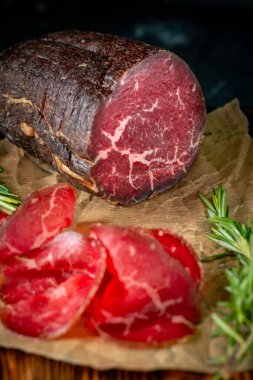 Kesme tahtasında tütsülenmiş Bresaola dilimlenmiş. İtalyan jambonu.