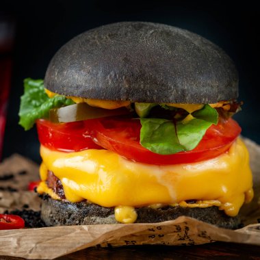 Tahta bir tahtanın üzerinde siyah ekmekli çizburger ev yapımı Japon Burger 'ini kapat.