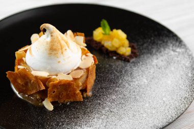 Beyaz arka planda siyah bir tabakta kremalı elmalı turta. Fındıklı Charlotte tatlısı.