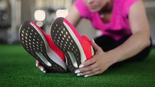 Γυναίκα καταλληλότητας σε ροζ παπούτσια close-up. Η άσκηση στο γυμναστήριο ή σπίτι, τέντωμα, λεπτομέρεια από όμορφα πόδια άλματα. Αθλήτρια που εκτείνεται σε πάνινα παπούτσια. — Αρχείο Βίντεο