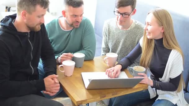 Grupo feliz de amigos ou colegas de negócios bebendo café e rindo e usando o computador juntos em um pequeno café ou bar de vinhos — Vídeo de Stock