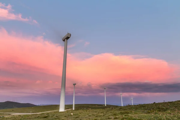 Storm sunset with spectacular rays between the windmills, with the clouds of the sky changing color, on an autumn day in the Sierra de Bobia, Asturias