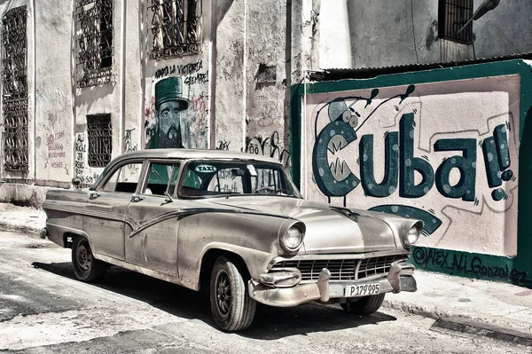 Viejo coche en las calles de La Habana con paredes pintadas con propaganda cubana —  Fotos de Stock
