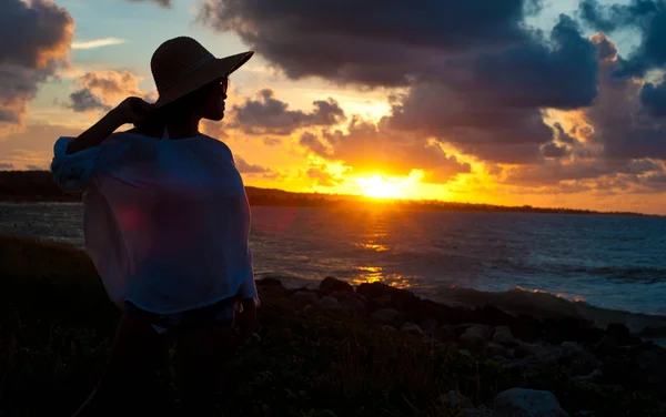 Silhuett av jente på stranden med hatt ved solnedgang – stockfoto