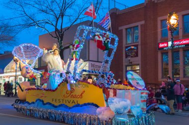 Penticton, British Columbia/Kanada - 3 Aralık 2016: Bayan Penticton kalabalığa Penticton şeftali Festivali float türünden Penticton şehir merkezinde yıllık Noel Baba geçit sırasında dalgalar.